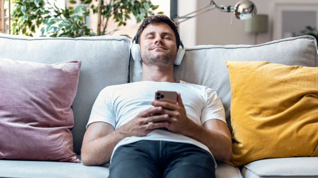Mann auf Sofa mit Kopfh&ouml;rern 