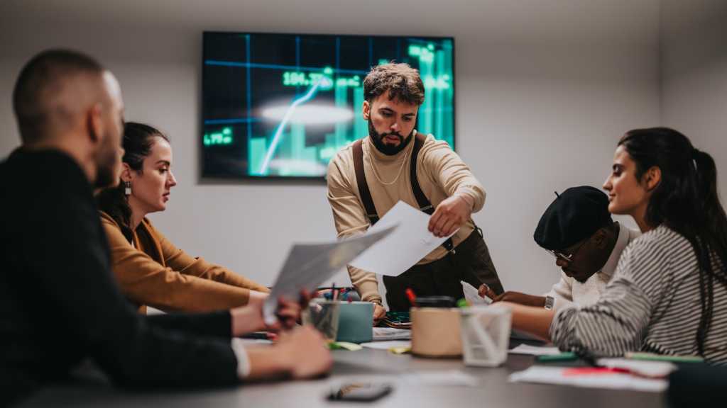 A collaborative team working during a meeting, analyzing financial data. People are actively discussing charts, showcasing a professional workspace and innovative ideas.
