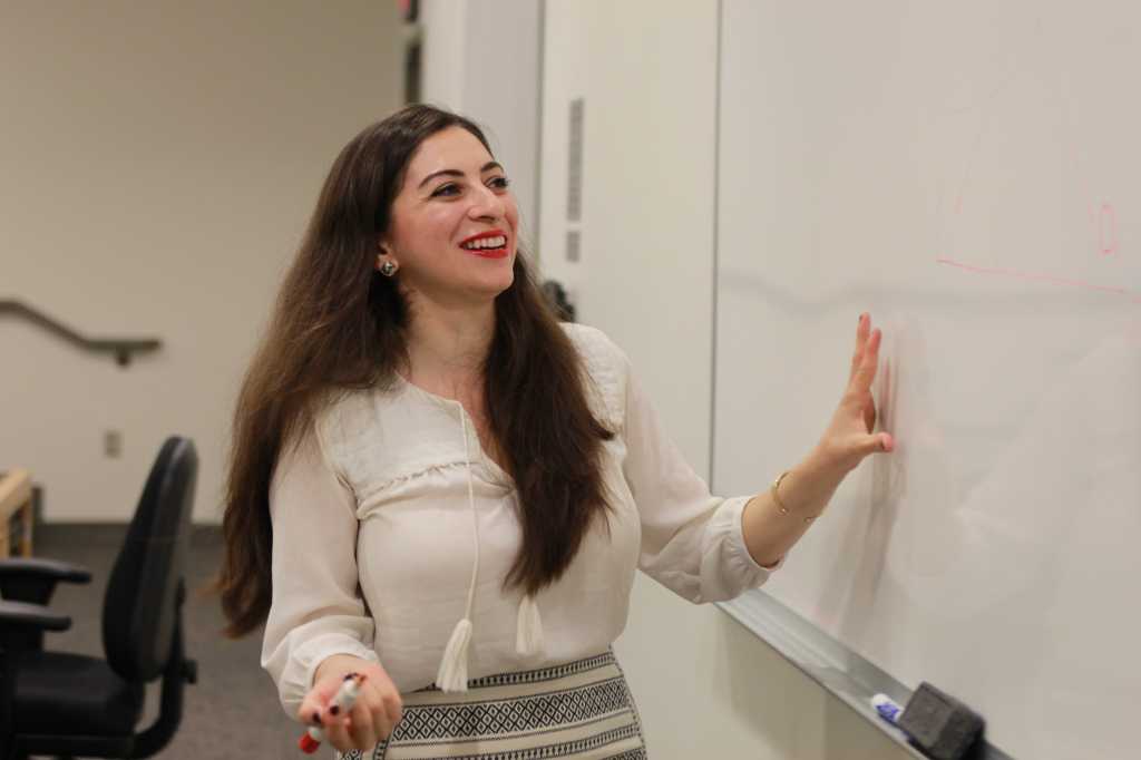 photo of liya palagashvili smiling and gesturing toward whiteboard